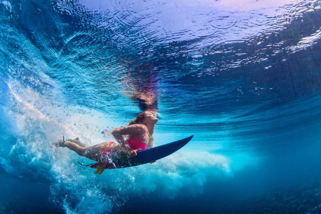 A person on a surfboard under the water.